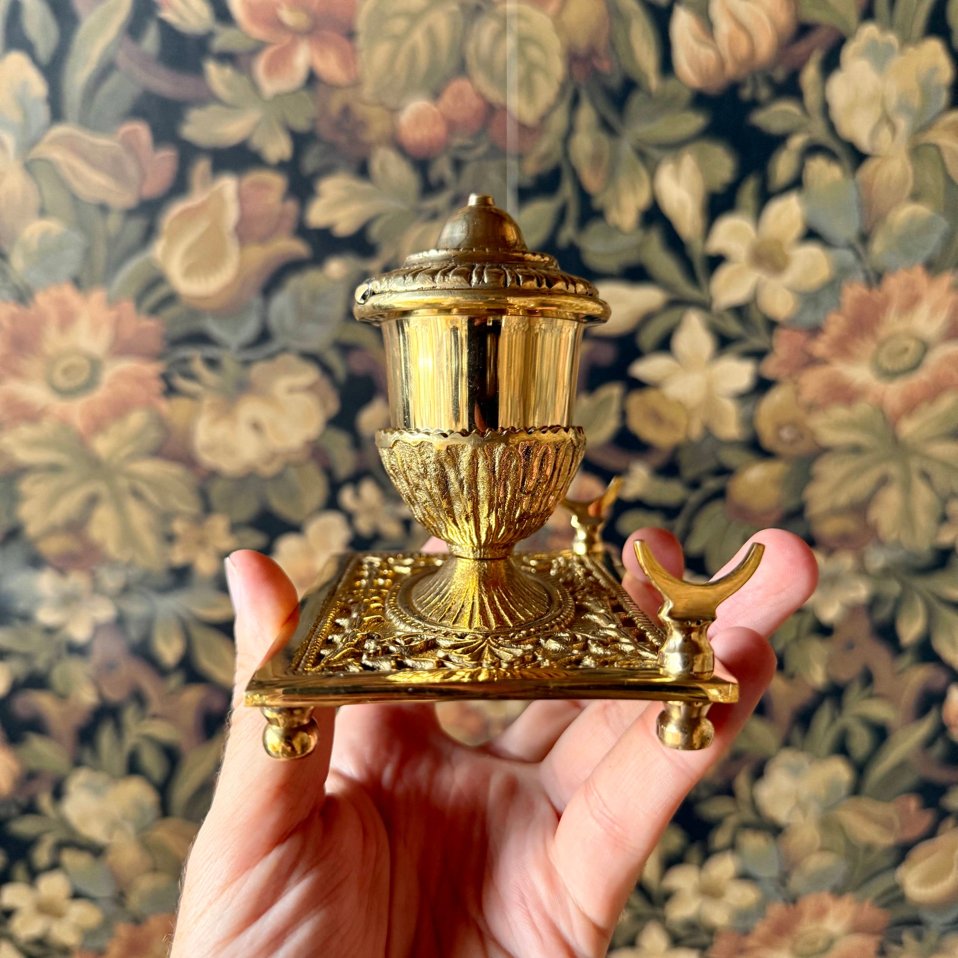A detailed shot of the solid brass inkwell, showcasing its intricate antique-style engravings, hinged lid, and built-in pen holder.