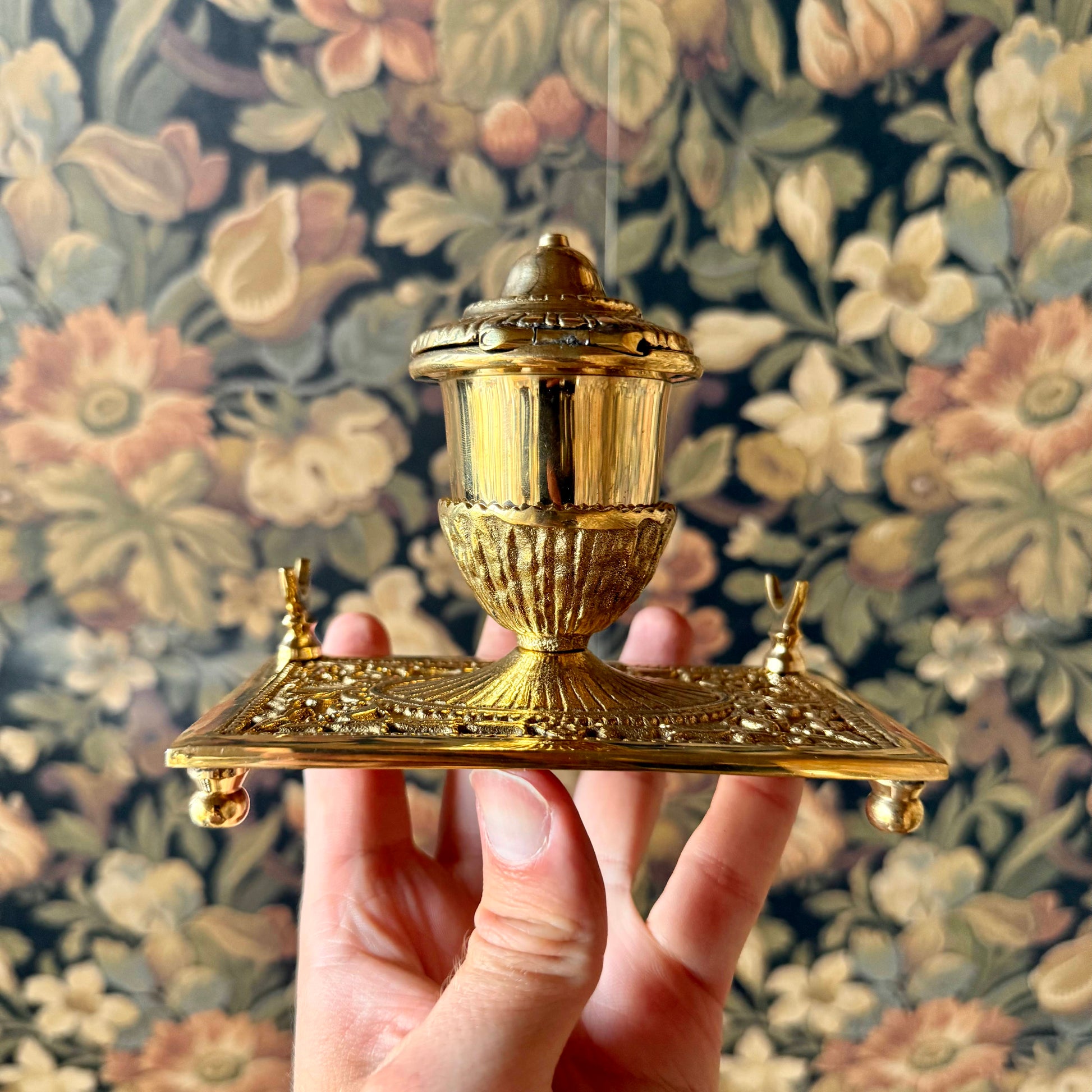 A detailed shot of the solid brass inkwell, showcasing its intricate antique-style engravings, hinged lid, and built-in pen holder.