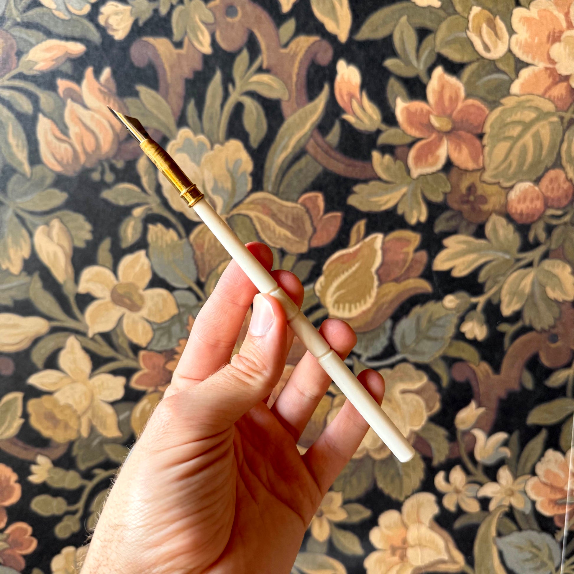 A close-up of the ox bone nib pen with its contoured handle, removable metal nib, and smooth, polished surface.