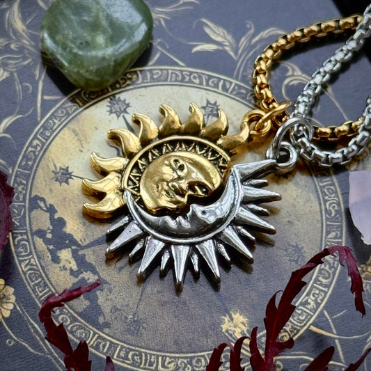 Sun and moon pendant on a chain against an astrological background