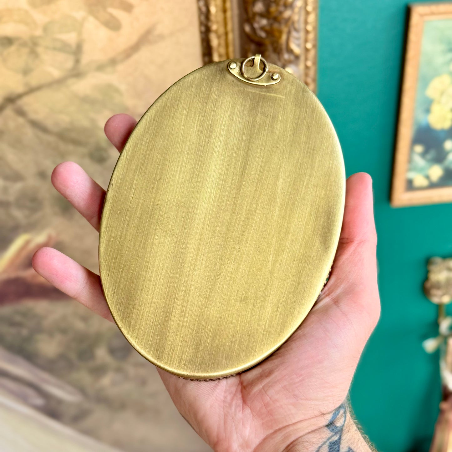 The solid brass backing of the frame, featuring an attached brass hanger for easy wall mounting.