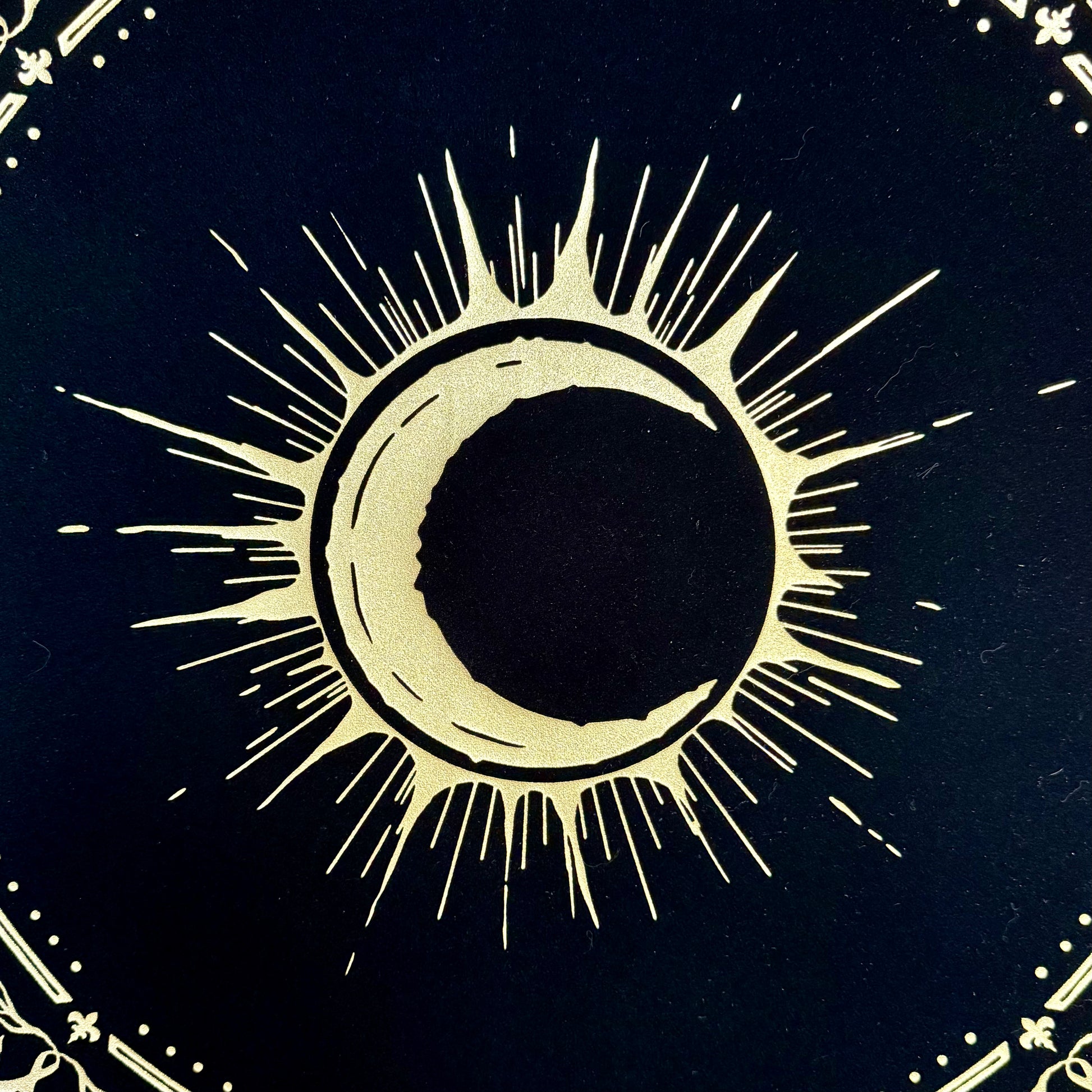 A detailed close-up of the gold foil emblem, intricately hand-stamped on the luxurious velvet fabric of the Eclipsa Altar Cloth.