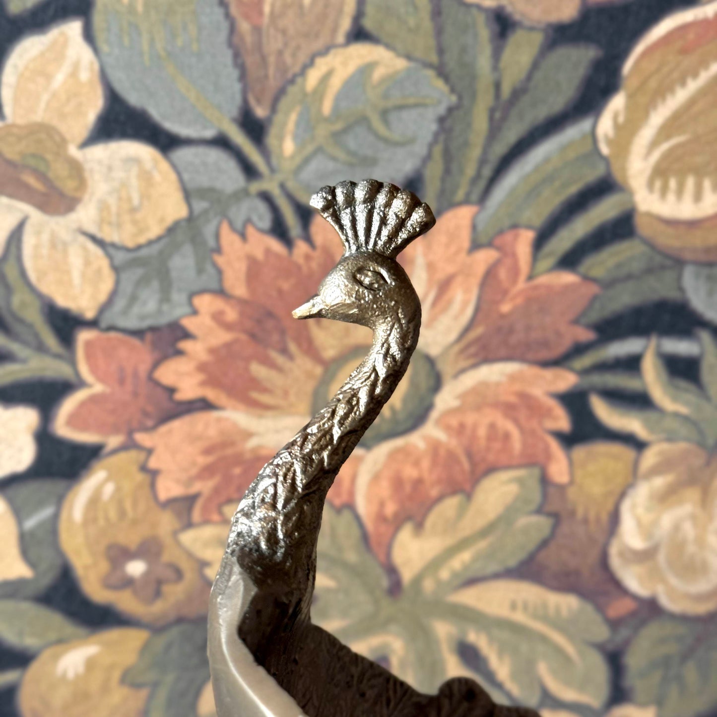 Decorative metal bird figure on a floral patterned fabric background