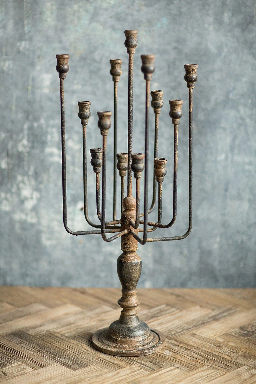 Decorative metal candelabra on a wooden surface with a gray textured background
