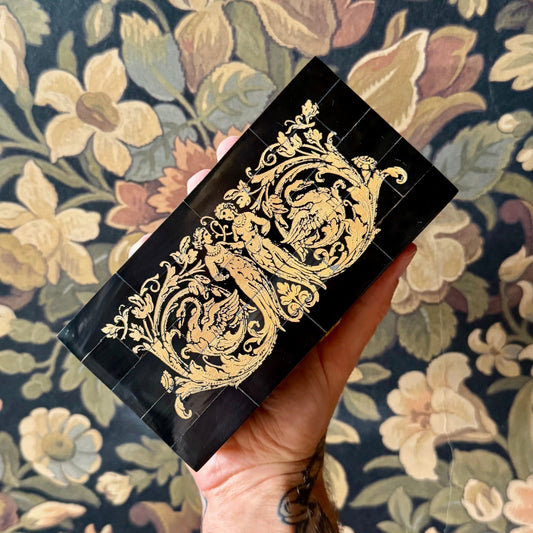 A rectangular black horn box with a mosaic tile exterior made from real water buffalo horn. The box features a brass latch and is displayed closed on a neutral background.