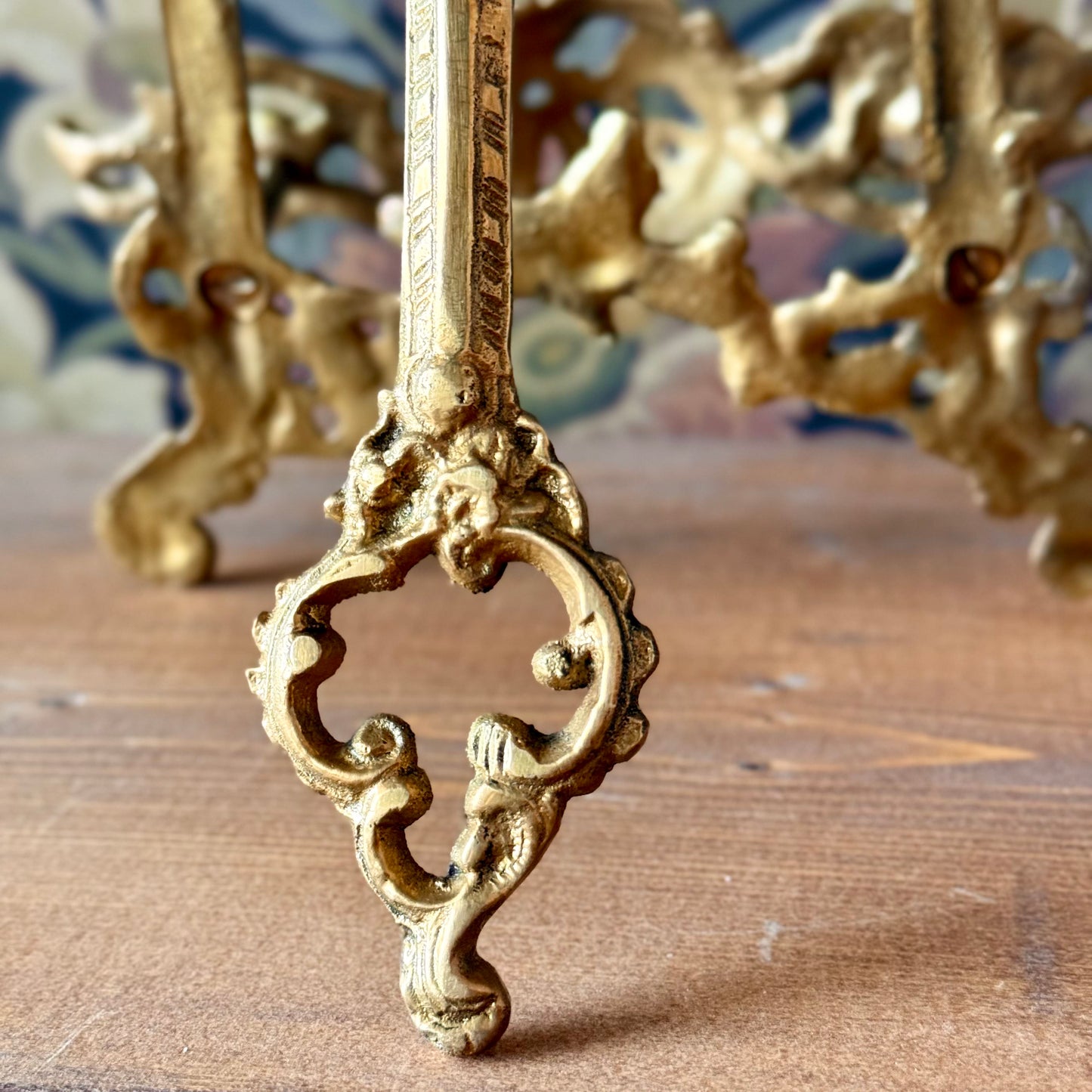 Victorian brass easel displayed on a wooden altar table holding an open tarot journal, surrounded by candles and dried flowers.