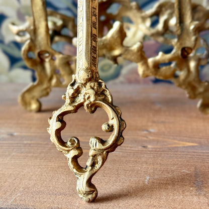 Victorian brass easel displayed on a wooden altar table holding an open tarot journal, surrounded by candles and dried flowers.