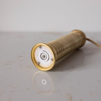 Brass-colored salt & pepper mill on a light gray surface