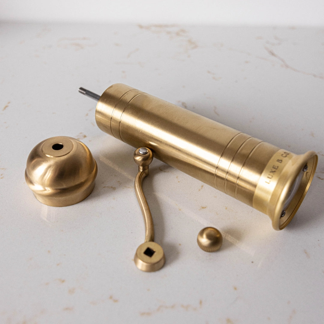 Brass pepper grinder with parts on a marble surface