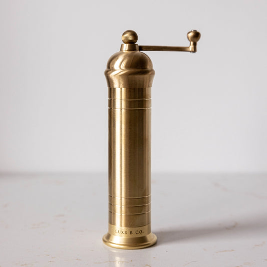 Brass pepper grinder on a light gray background