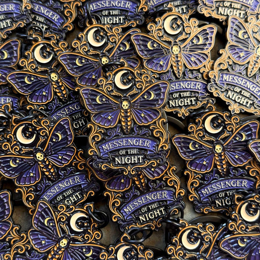 Moth keychains with 'Messenger of the Night' text and decorative elements on a patterned background.