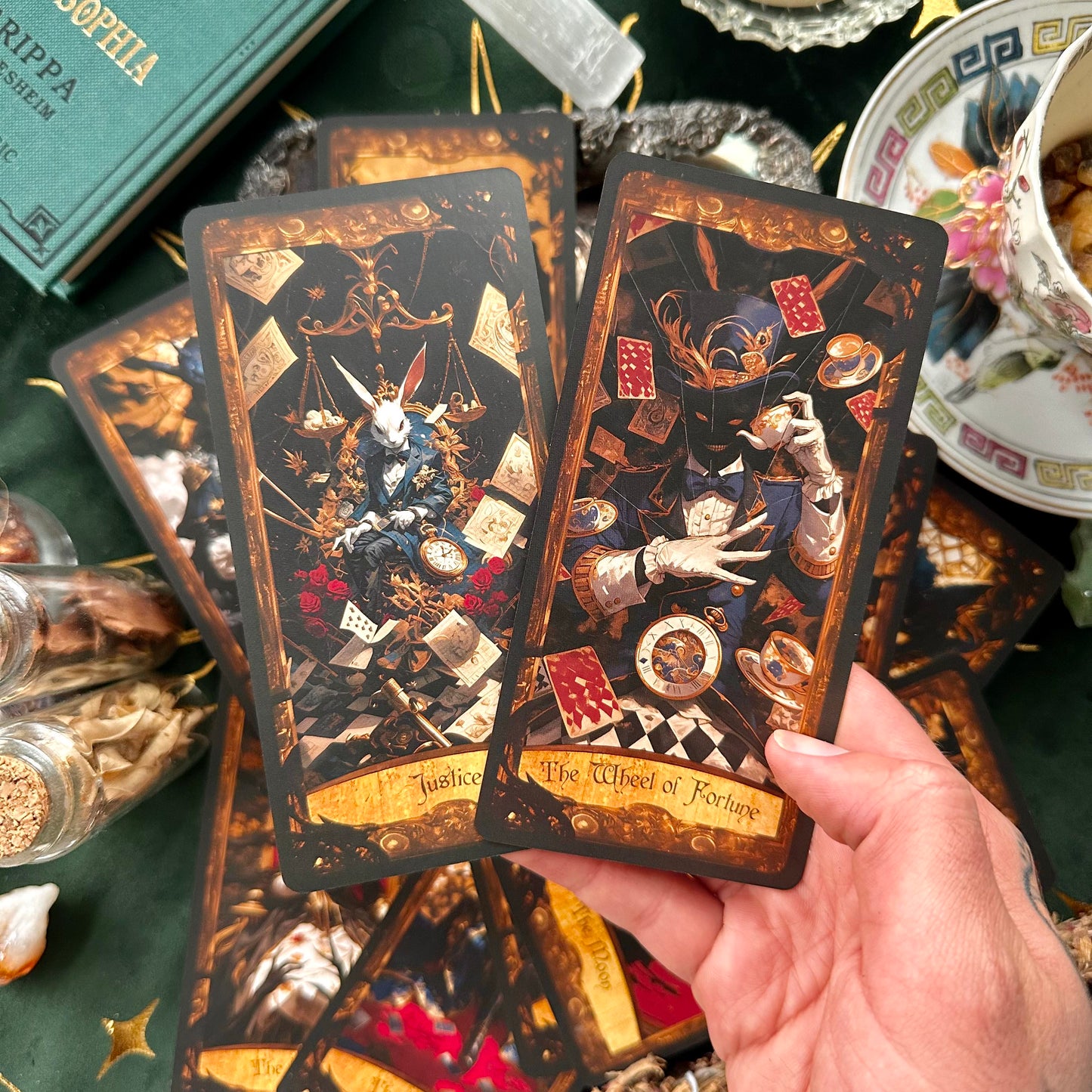 Two side-by-side tarot cards; one features the White Rabbit as the embodiment of Justice, with scales in one hand and a sword in the other, while the Mad Hatter represents the Wheel of Fortune, surrounded by spinning symbols of chance and change.