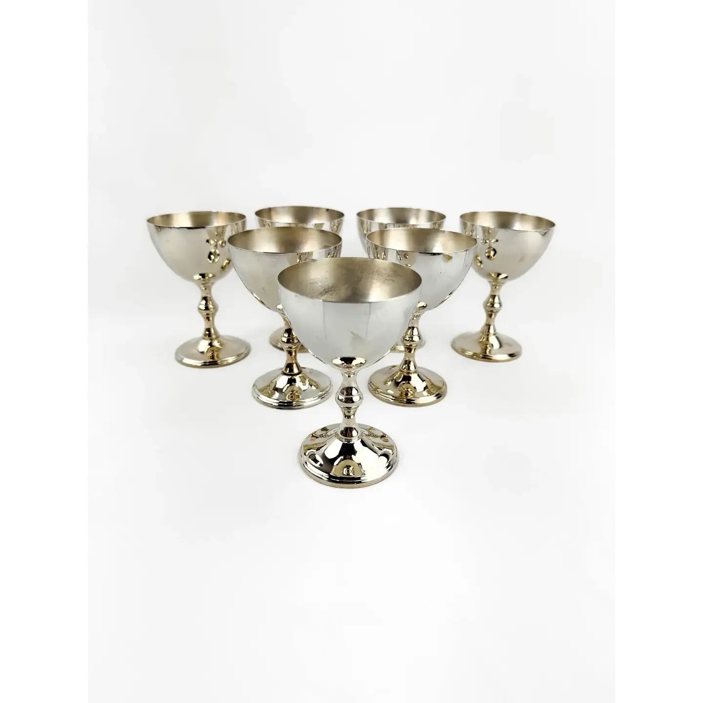 Six polished silver goblets arranged in a semi-circle on a plain white background.