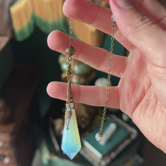 Victorian-inspired obsidian pendulum adorned with brass detailing. The deep black obsidian stone is polished to a smooth finish and hangs from a brass chain, suitable for dowsing or as an elegant decorative item.