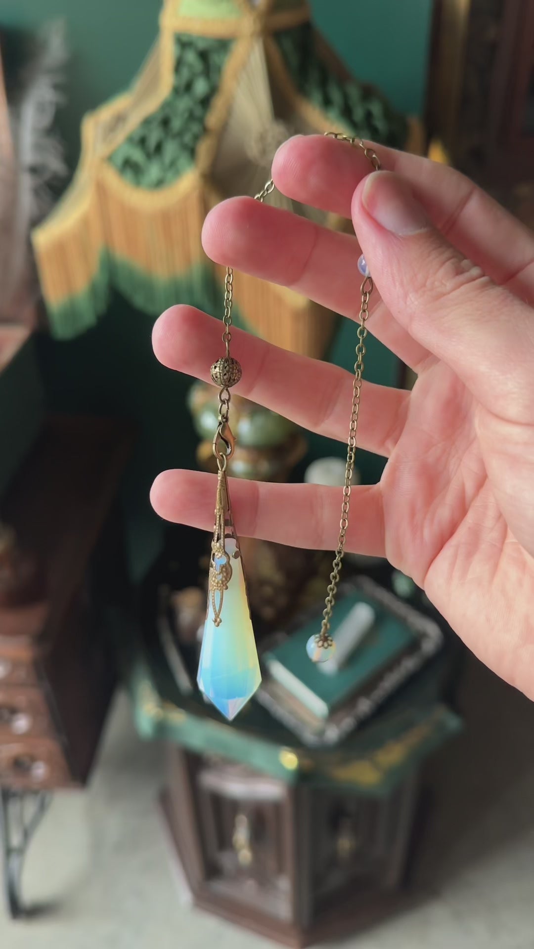 Victorian-inspired obsidian pendulum adorned with brass detailing. The deep black obsidian stone is polished to a smooth finish and hangs from a brass chain, suitable for dowsing or as an elegant decorative item.